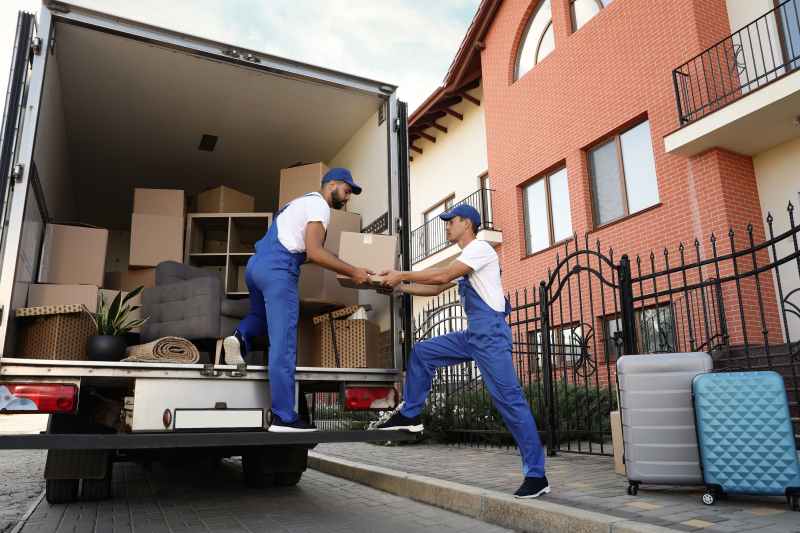 Workers unloading boxes from van outdoors.